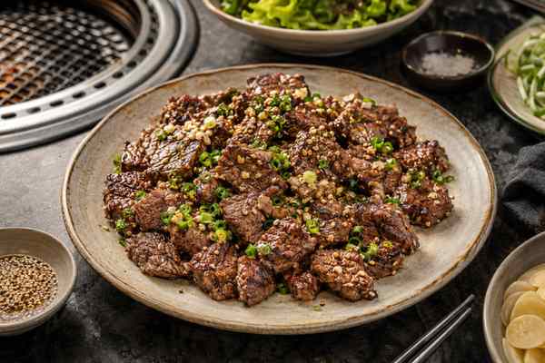 Finished Jumulleok Sesame-Garlic Steak Bites presented in a warm Korean dining setting.