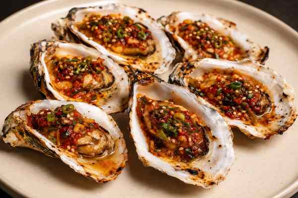 Finished Scallion-Gochujang Grilled Oysters presented in a warm Korean dining setting.