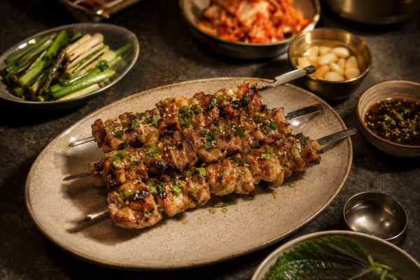 Finished Garlic-Scallion Chicken Skewers presented in a warm Korean dining setting.