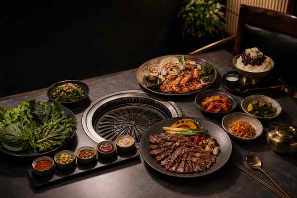 A complete Korean barbecue table with grilled dishes, banchan, greens, sauces, and dessert.